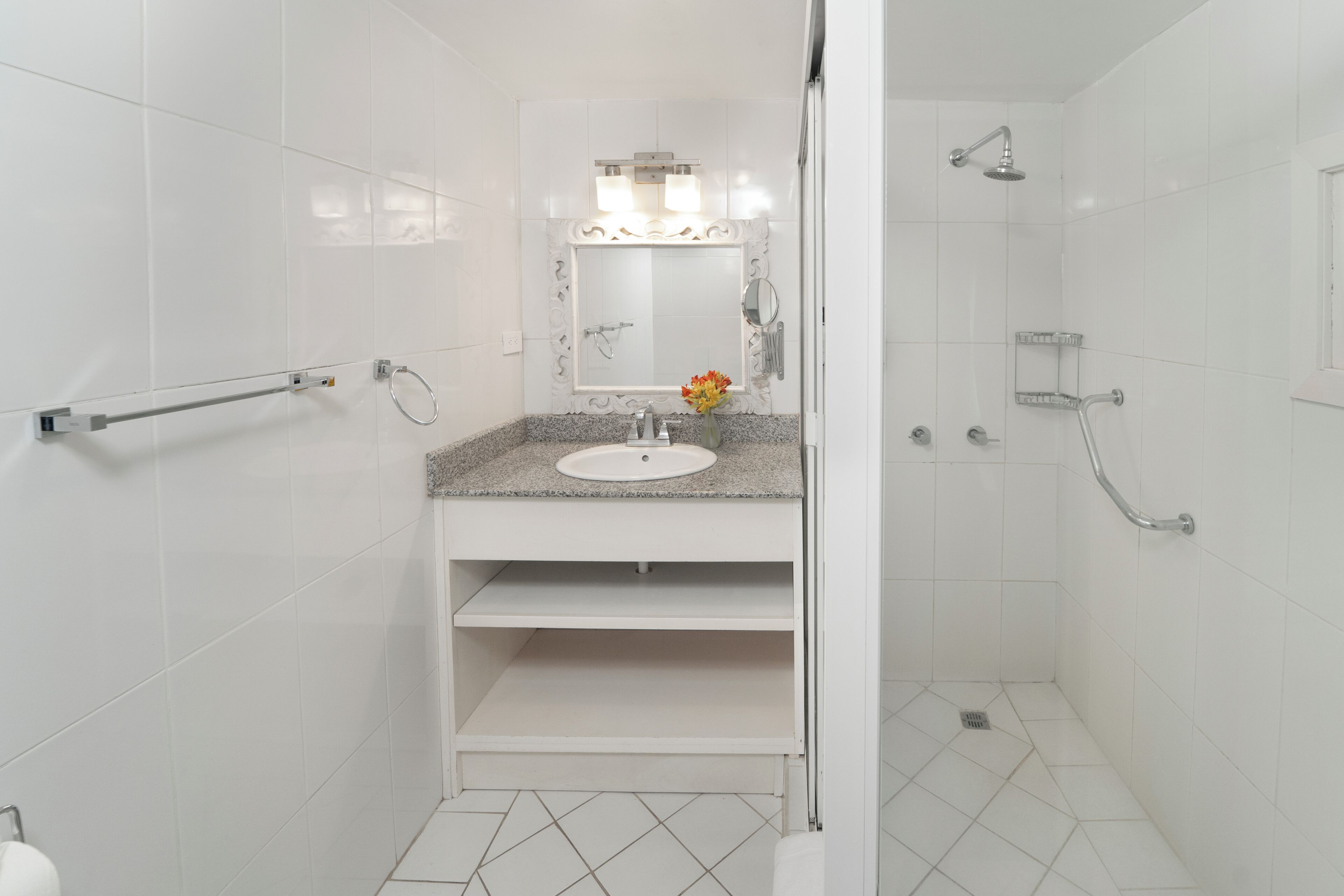 A bathroom with a sink, mirror, shower, and grab bars.