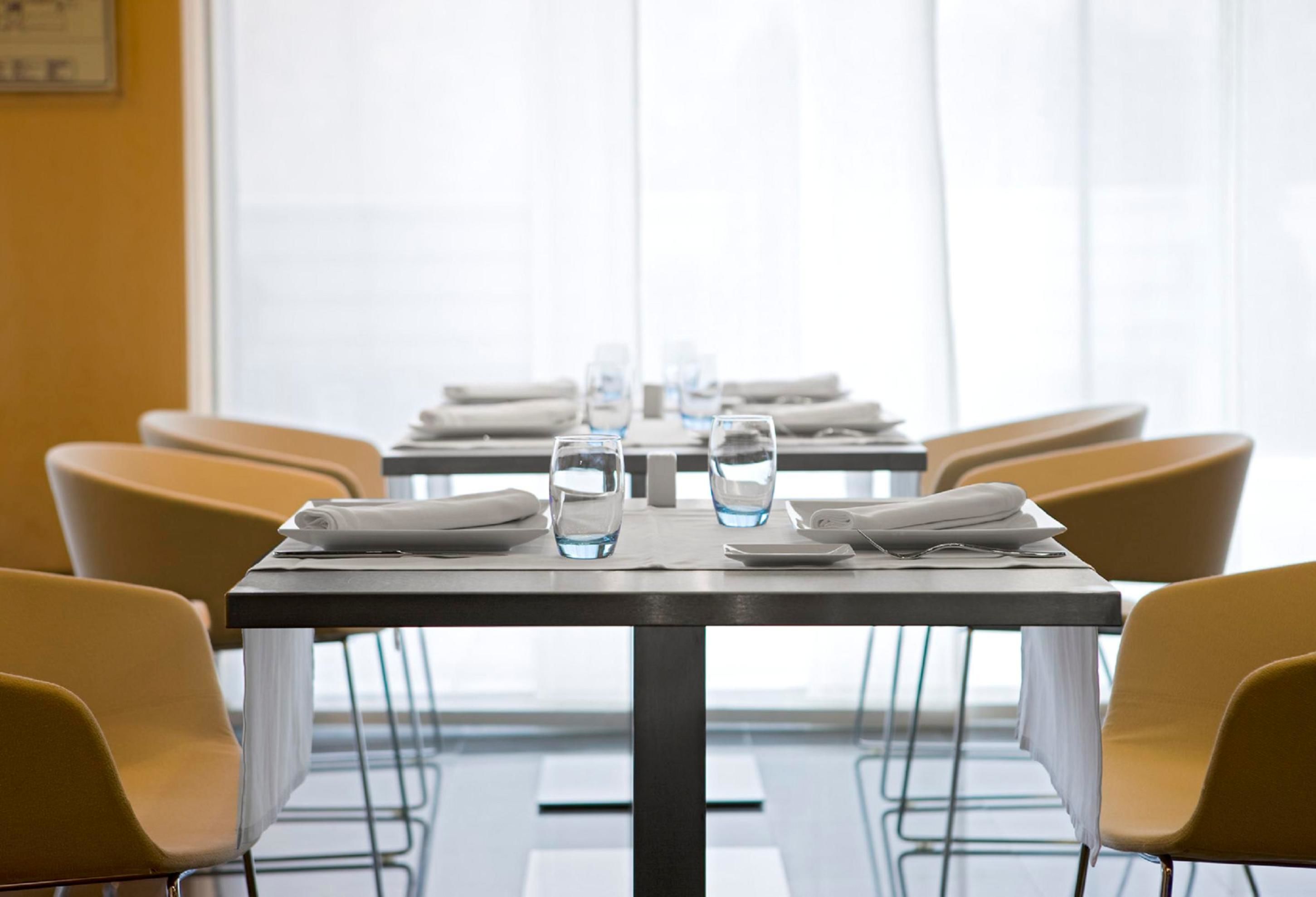 Een vergaderzaal met een lange tafel, stoelen en waterglazen.