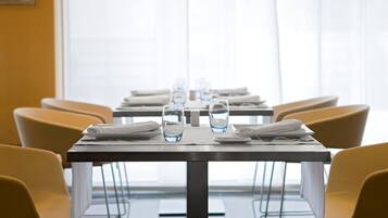 Een vergaderzaal met een lange tafel, stoelen en waterglazen.
