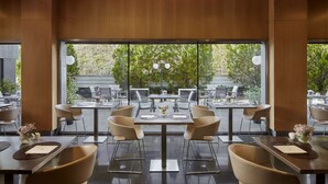 Un restaurante moderno con ventanas amplias, varias mesas y sillas dispuestas para comer.