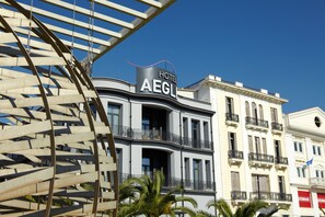 A hotel with a modern facade, balconies, and a clear blue sky in the background.