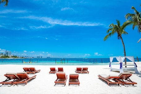 En la playa, arena blanca, sillas reclinables de playa, toallas de playa