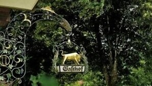 A decorative metal sign with a bull and the word "Gathof" hanging from a tree in a lush garden. - Hotel Ochsenwirtshof (Bad Rippoldsau-Schapbach)