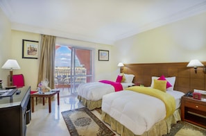 A hotel room with two beds, a desk, a chair, a table, and a balcony with a view. - Mogador Kasbah (Marrakech)