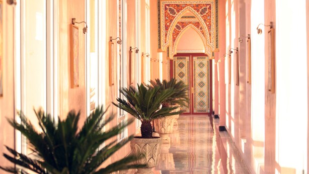 A long, well-lit hallway with potted plants and ornate doors. - Mogador Kasbah (Marrakech)