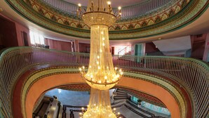 A grand interior with a large, ornate chandelier, multiple balconies, and a central staircase. - Mogador Kasbah (Marrakech)
