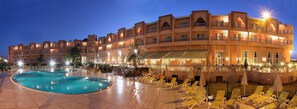 A hotel with a large swimming pool, multiple balconies, and outdoor seating areas. - Mogador Kasbah (Marrakech)