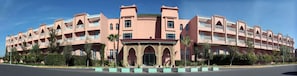 A pink multi-story hotel with balconies and a central entrance with decorative arches. - Mogador Kasbah (Marrakech)