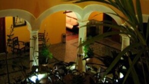 A courtyard with a covered seating area, columns, and potted plants. - Hotel Castelmar (Campeche)