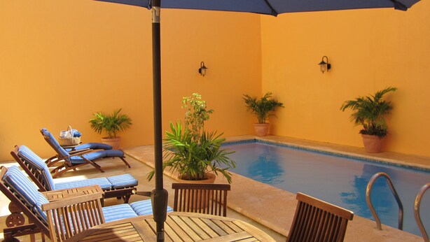 An indoor pool area with lounge chairs and potted plants. - Hotel Castelmar (Campeche)