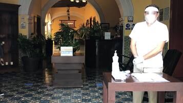 Un vestíbulo de hotel con suelo de baldosas, una recepción y una araña.