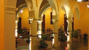 A spacious corridor with arches, potted plants, and a tiled floor. - Hotel Castelmar (Campeche)