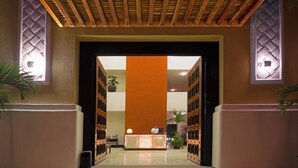 A reception area with a wooden ceiling, a reception desk, and a large orange wall. - Pueblito Escondido Luxury by Mistik (Playa del Carmen)
