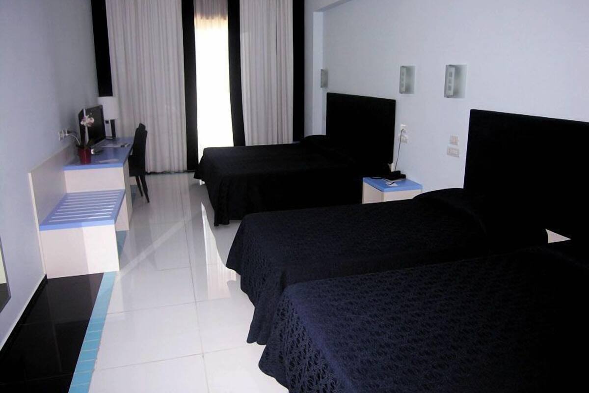 Una habitación de hotel con dos camas, un escritorio con computadora y una silla.