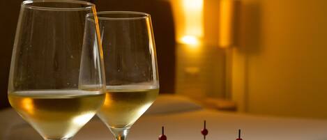 Two wine glasses on a table with a plate of appetizers.