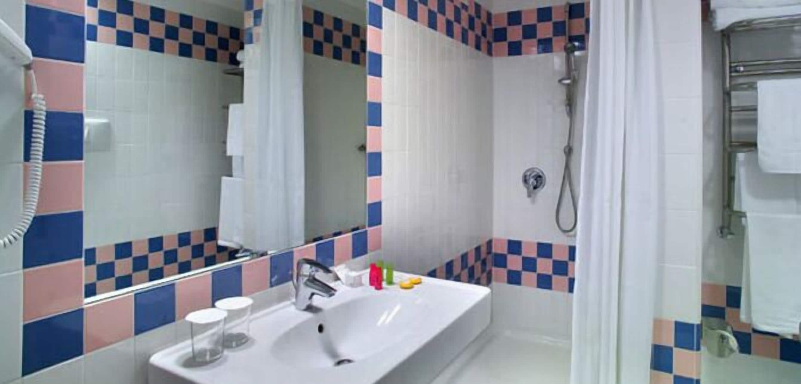 A bathroom with a white sink, mirror, and shower.