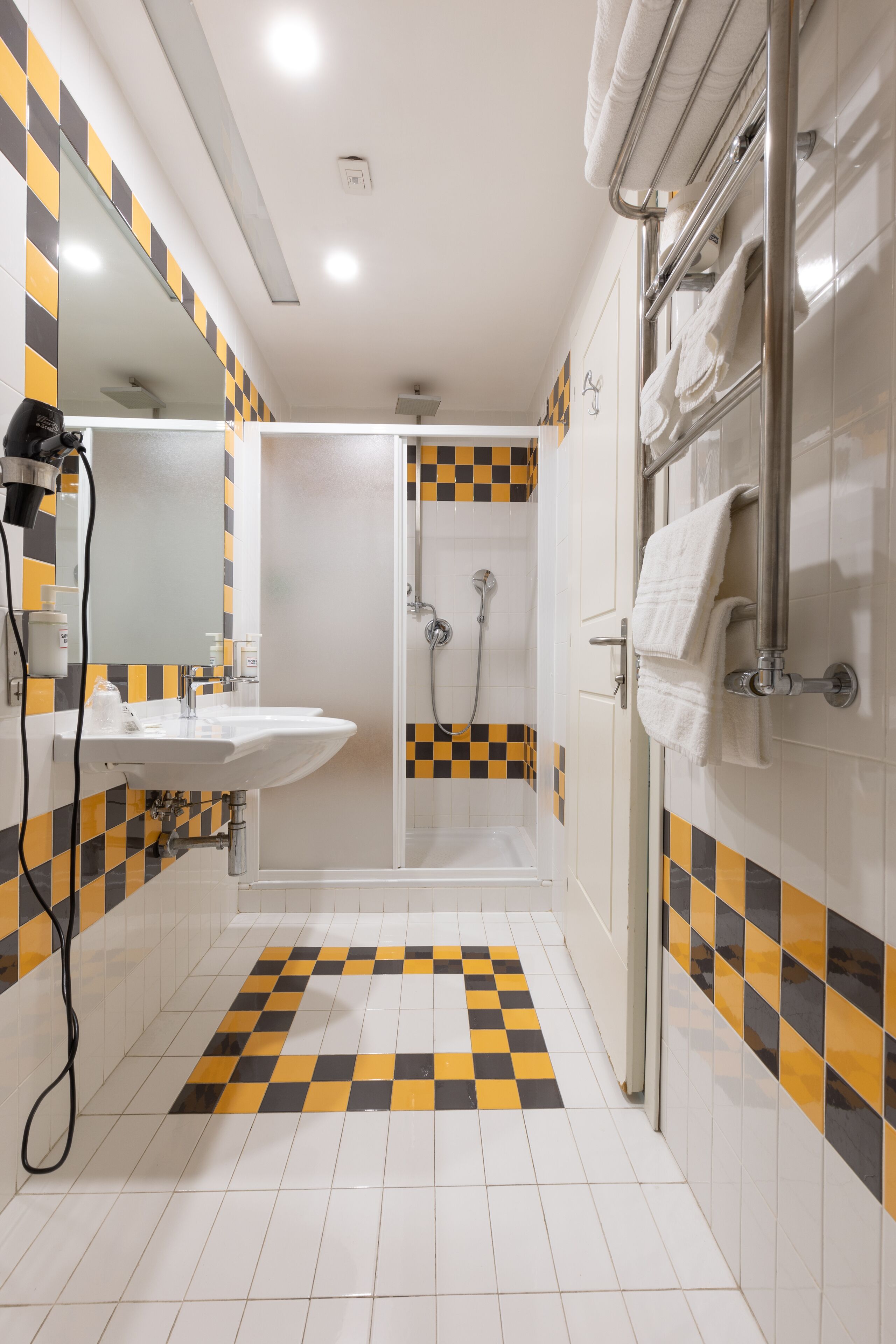 A bathroom with a checkered floor, a sink, a mirror, and a shower area.