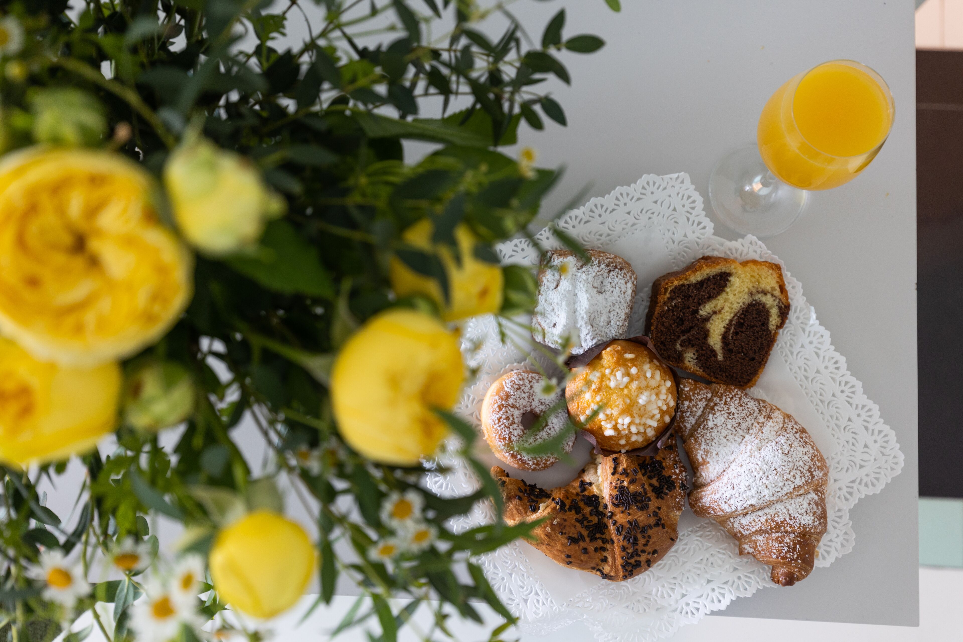 A table with pastries, a glass of orange juice, and a white lace doily.