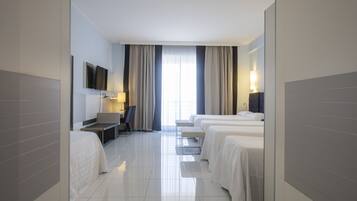 Habitación de hotel con cama, escritorio, silla y televisor en la pared.