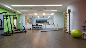 Ein Fitnessraum mit Trainingsgeräten, einem Gewichtständer und einem Yoga-Ball.