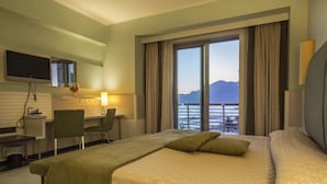 Ein Hotelzimmer mit Bett, Schreibtisch, Stuhl, Fernseher und Meerblick.