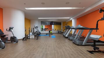Une salle de sport équipée de tapis de course, de vélos d’appartement et d’appareils de musculation.