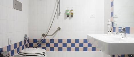 A bathroom with a checkered tile floor, a sink, a toilet, and a shower with grab bars.