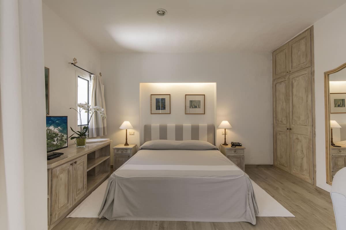 Een slaapkamer met een bed, nachtkastjes, een dressoir en een kledingkast.