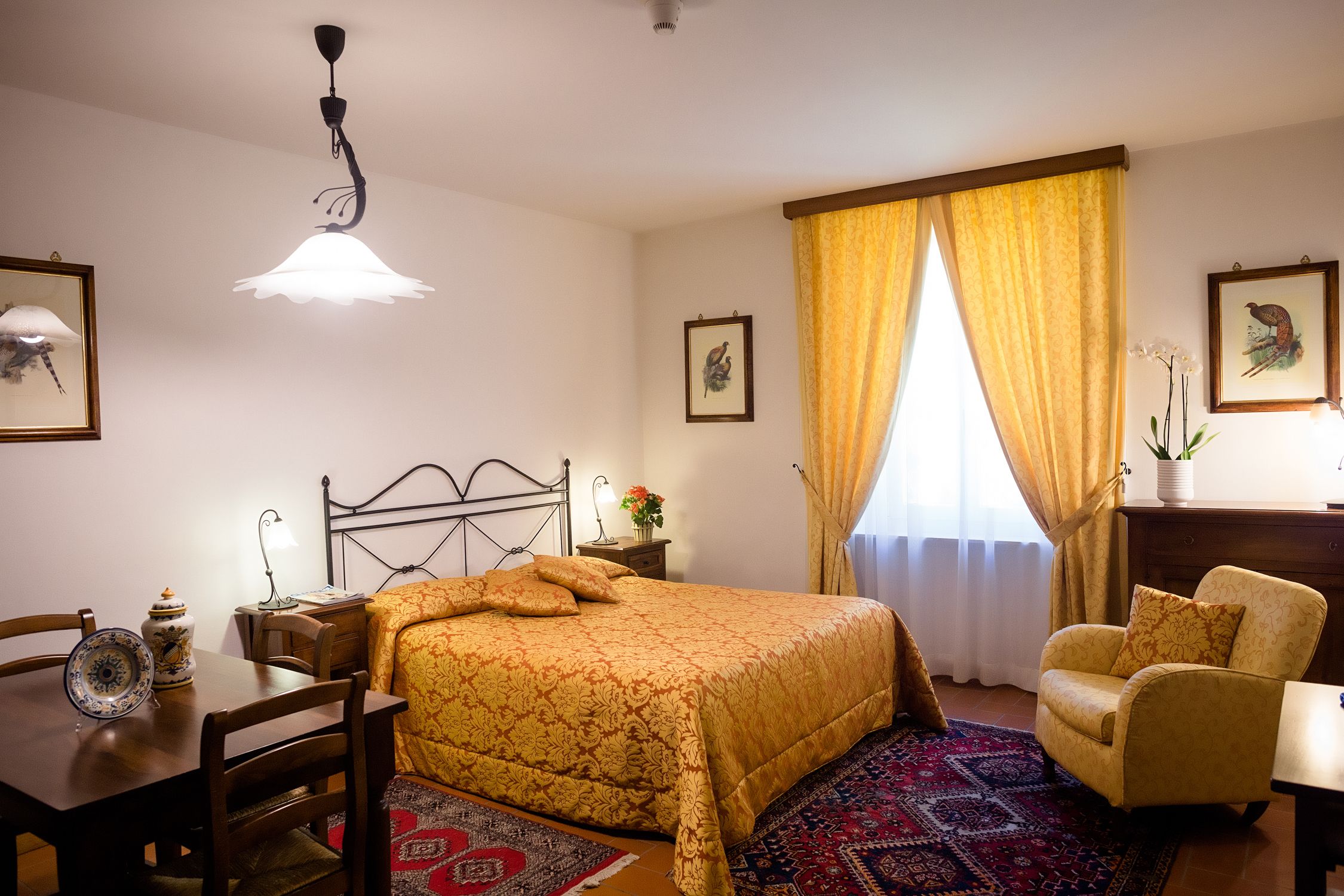 Una camera da letto ordinata con un letto, una sedia, un tavolo e una lampada.