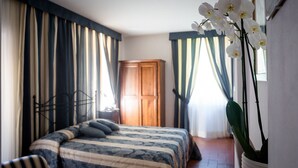Un dormitorio con cama, cortinas, armario y una planta en maceta.