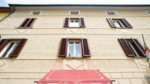 Fachada de edificio con varias ventanas, un toldo rojo con la inscripción "La Fenice" y una puerta con un arco decorativo.