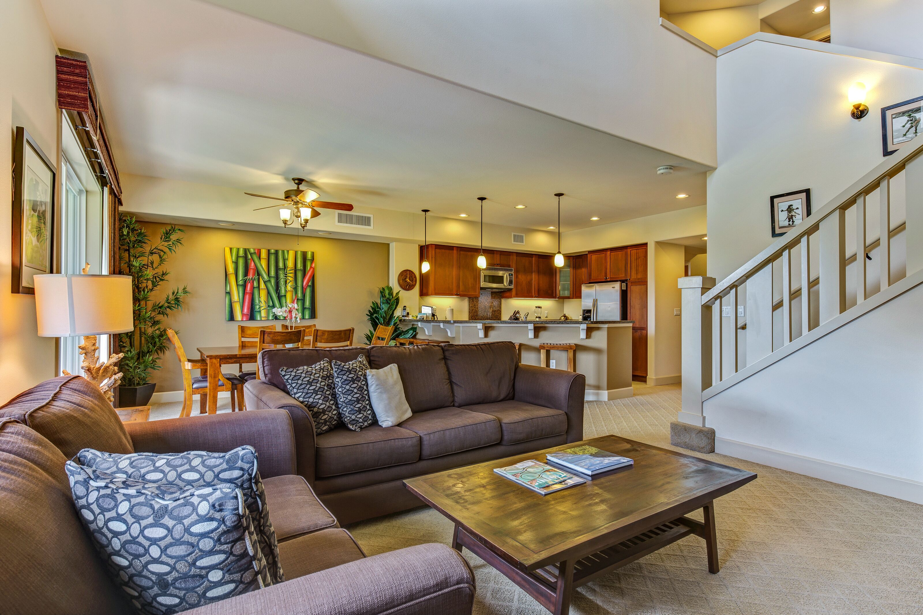 A spacious living room with a brown sofa, a wooden coffee table, and a dining area in the background.