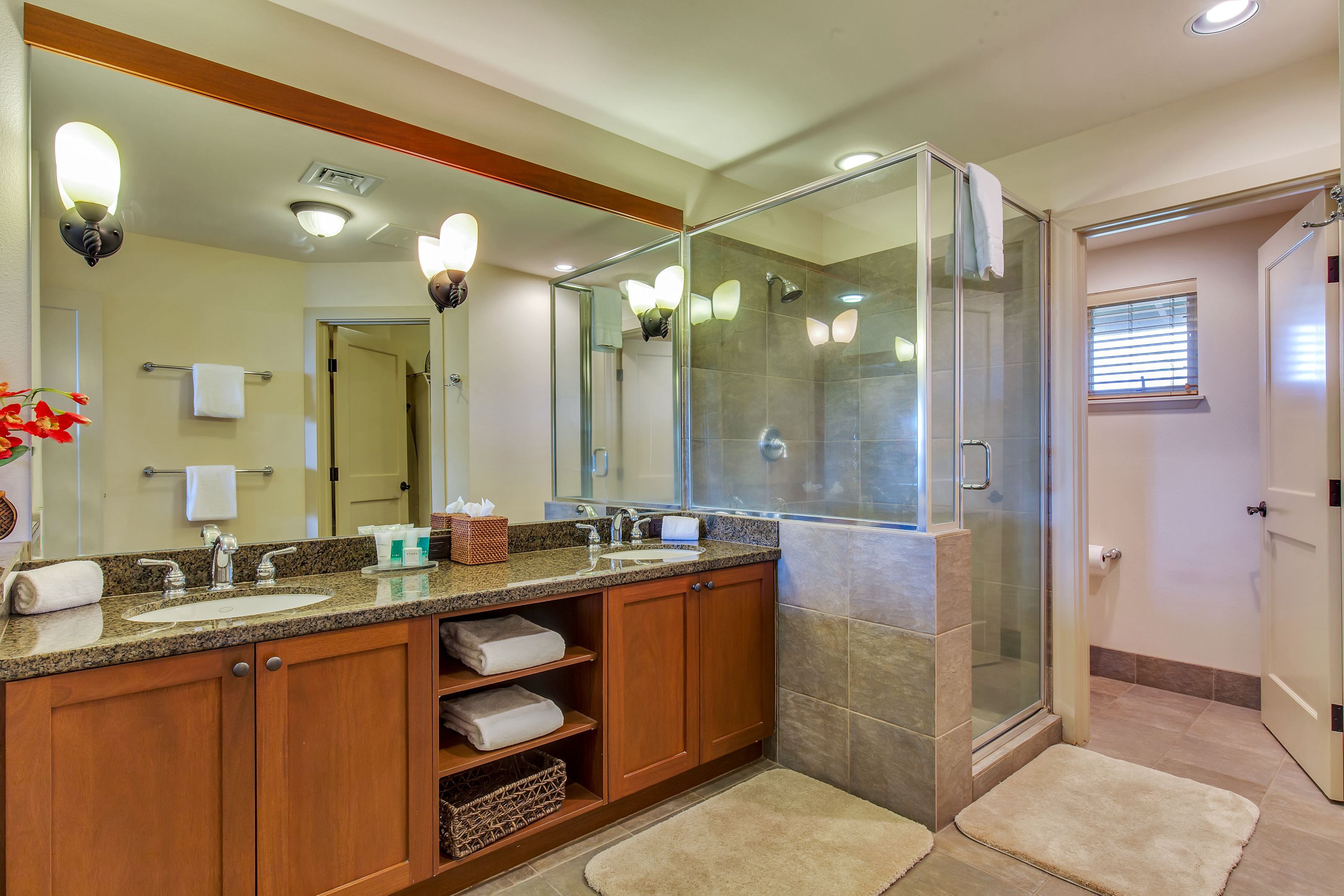 A modern bathroom with a glass-enclosed shower, a large mirror, and wooden cabinets.