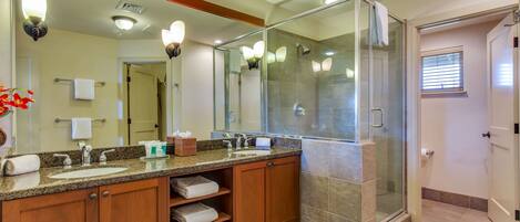 A modern bathroom with a glass-enclosed shower, a large mirror, and wooden cabinets.