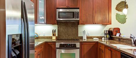 A kitchen with wooden cabinets, stainless steel appliances, granite countertops, and a built-in oven.