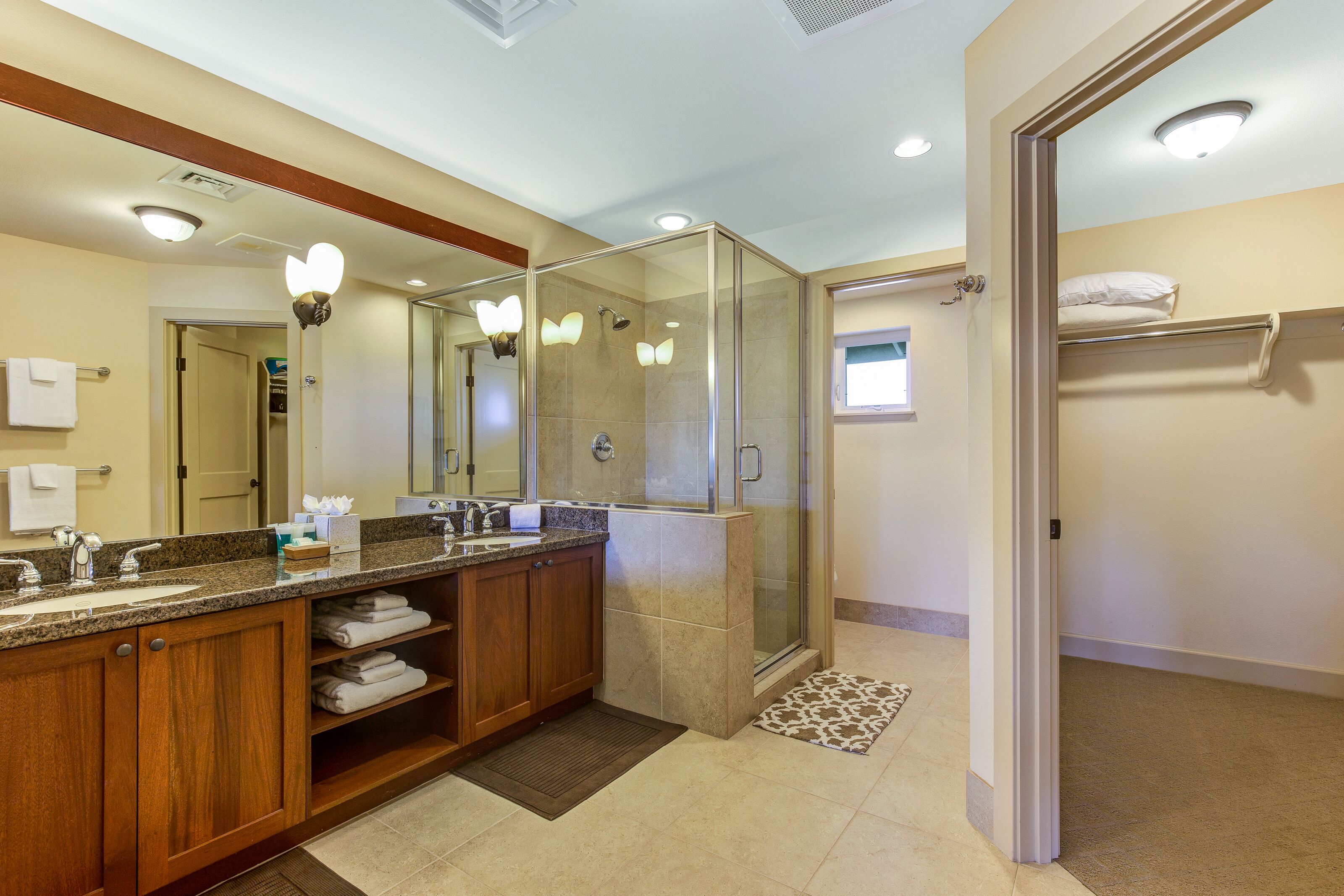 A modern bathroom with a large mirror, wooden vanity, and a glass-enclosed shower.