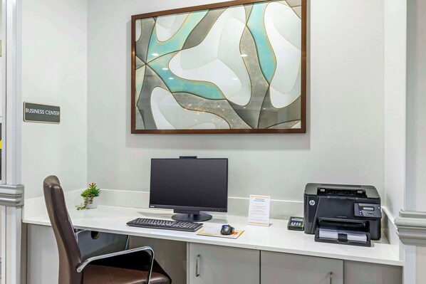 Escritorio de centro de negocios con computadora, impresora y un cartel que indica la ubicación.