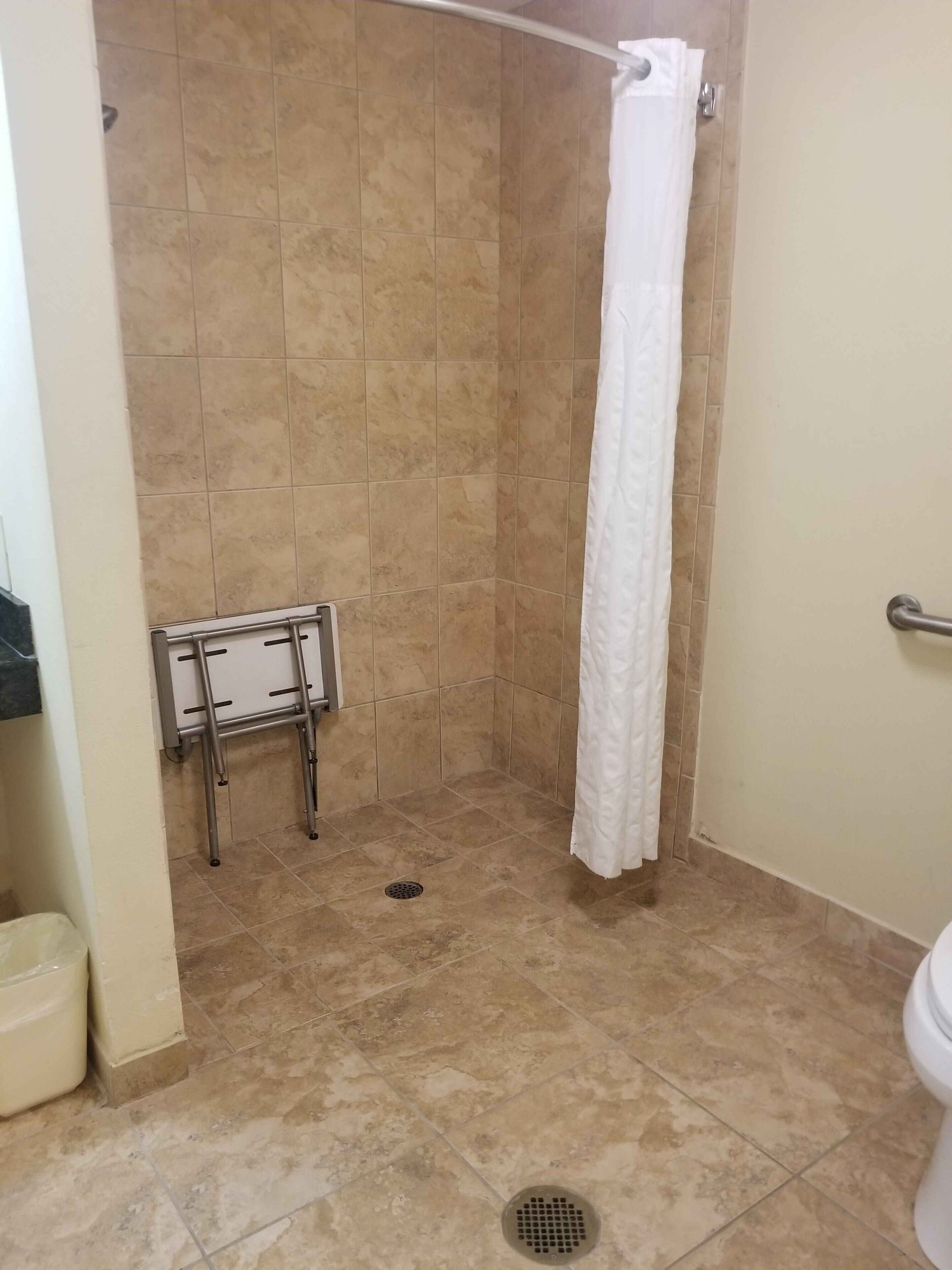 A small, tiled bathroom with a shower, a toilet, and a towel rack.