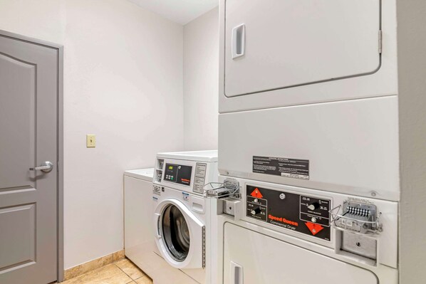 A compact laundry area with a front-loading washing machine and a stacked dryer. - Comfort Suites Valdosta Mall Area (Valdosta)