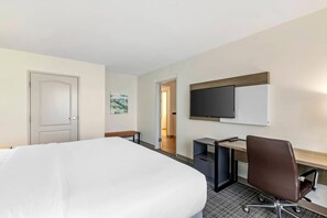 A hotel room with a bed, desk, chair, television, and artwork. - Comfort Suites Valdosta Mall Area (Valdosta)