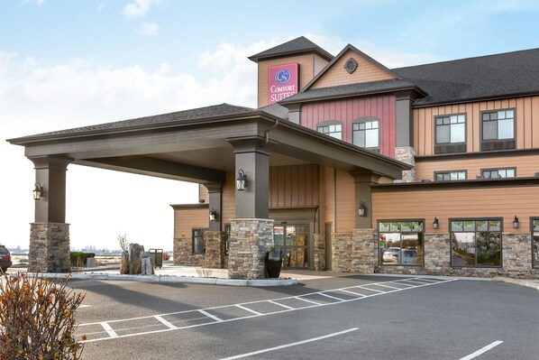 A hotel with a covered entrance, stone pillars, and a sign for Comfort Suites.
