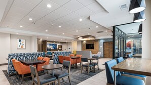 Een moderne hotellobby met zithoeken, een receptiebalie en een televisiescherm.