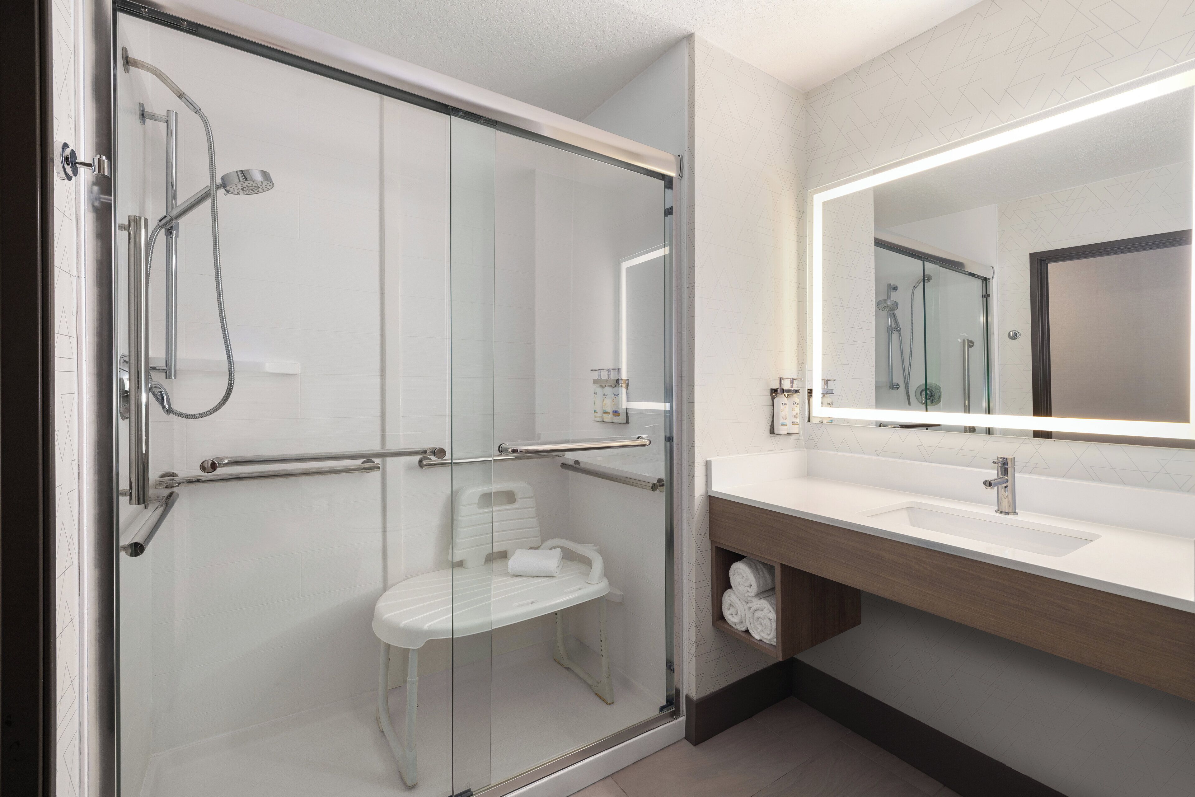 Une salle de bain moderne avec une douche à parois de verre, un lavabo blanc et un miroir au-dessus du meuble-lavabo.