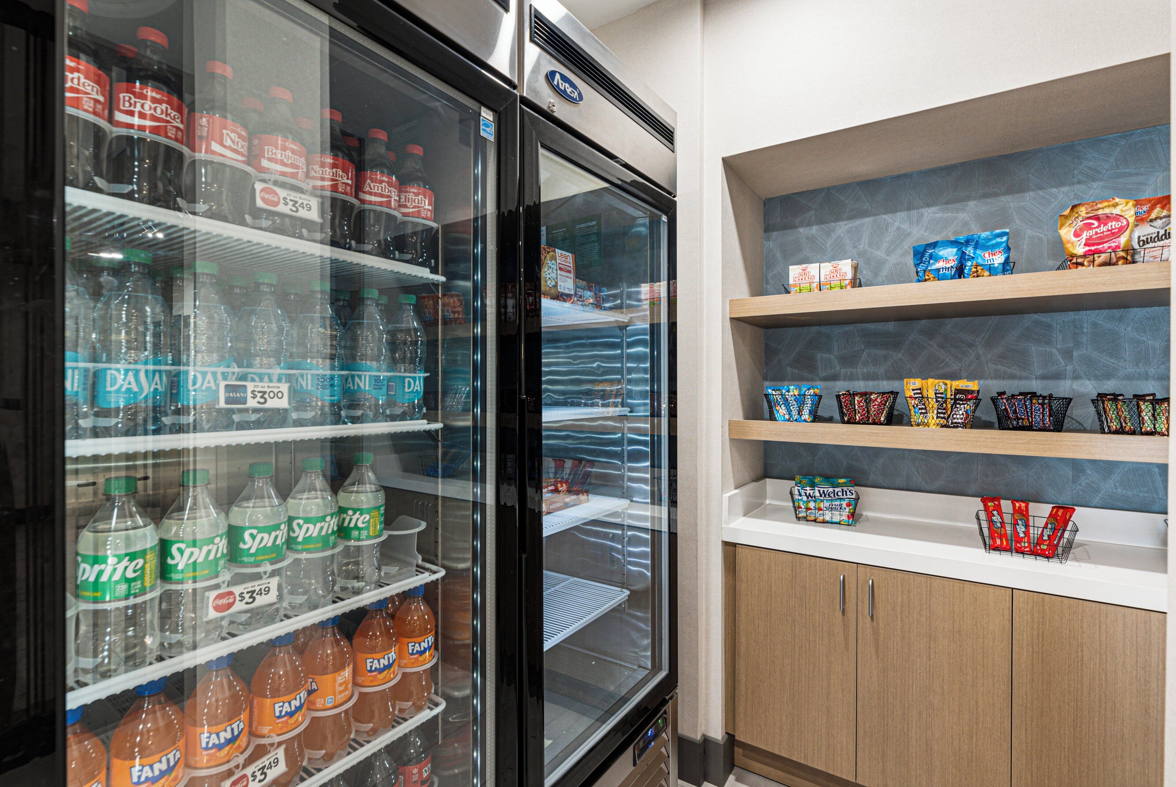 A refrigerated display case with various beverages and a shelf stocked with snacks.