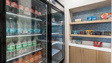 A refrigerated display case with various beverages and a shelf stocked with snacks.