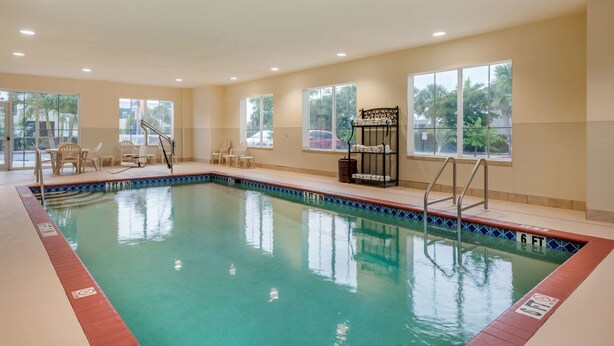 Une piscine intérieure à l’eau claire, dotée d’un poste de surveillance pour les sauveteurs et d’un espace détente avec des chaises.