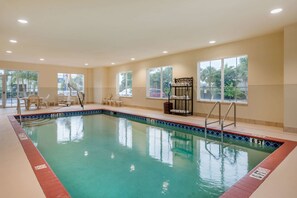 An indoor swimming pool with clear water, a lifeguard station, and a seating area with chairs. - Comfort Inn & Suites Fort Myers Airport (Fort Myers)