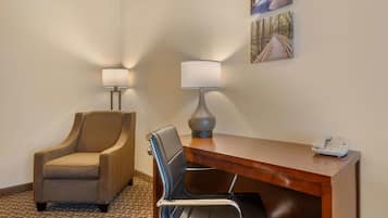 A hotel room with a desk, two chairs, a lamp, and a telephone.