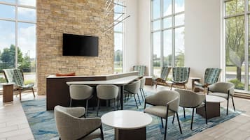A modern lounge area with a stone wall, a flat-screen TV, and comfortable seating.