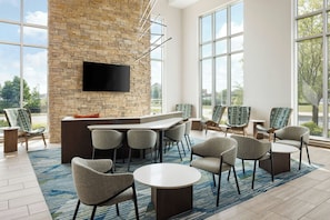 A modern lounge area with a stone wall, a flat-screen TV, and comfortable seating. - SpringHill Suites by Marriott Appleton (Appleton)